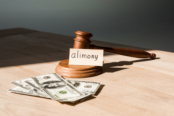 gavel near dollar banknotes and paper with alimony lettering on table   - Foto, afbeelding