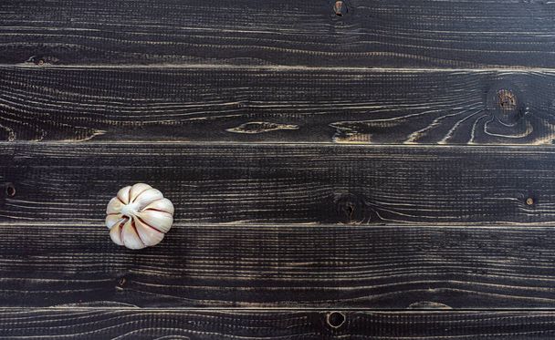 Κεφάλι από αποφλοιωμένο σκόρδο σε ένα παλιό ξεπερασμένο μαύρο ξύλινο τραπέζι - Φωτογραφία, εικόνα