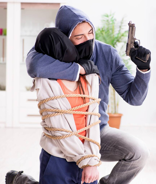 Uzbrojony mężczyzna napadający na młodą kobietę w domu - Zdjęcie, obraz
