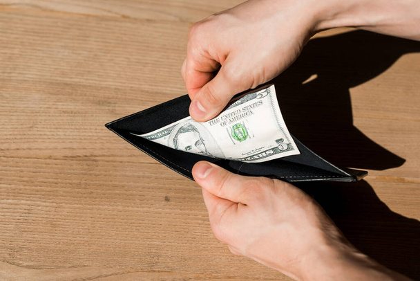 обрезанный вид человека, держащего бумажник с долларовой купюрой
  - Фото, изображение