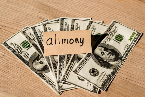 paper with alimony lettering on dollar banknotes  - Foto, Bild