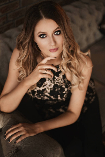 Young woman with blond hair and perfect trendy makeup. Beautiful blonde model girl with modish makeup, deep blue eyes and seductive look. Concept of modish official makeup and smooth skin - Fotó, kép