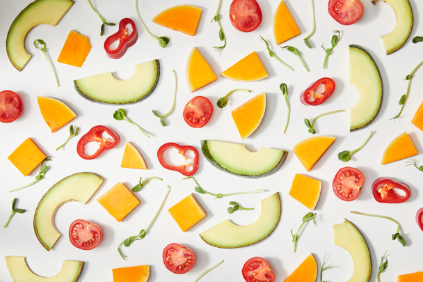 Плоский слой с микрозеленью, нарезанные овощи и слайсы авокадо на белом фоне
 - Фото, изображение