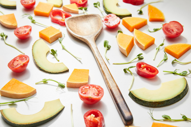 Селективный фокус лопатки с микрозеленью, срезать овощи и ломтики авокадо на белом фоне
 - Фото, изображение