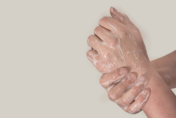 Вірус корони. Молодий хлопець у медичній захисній масці та миття рук з милом на сірому фоні. Захист від вірусів, інфекцій
 - Фото, зображення