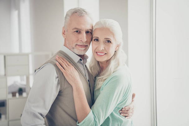 Close up photo of charming sweethearts retiree found true love cuddling dressed teal brown pullovers standing in room - 写真・画像