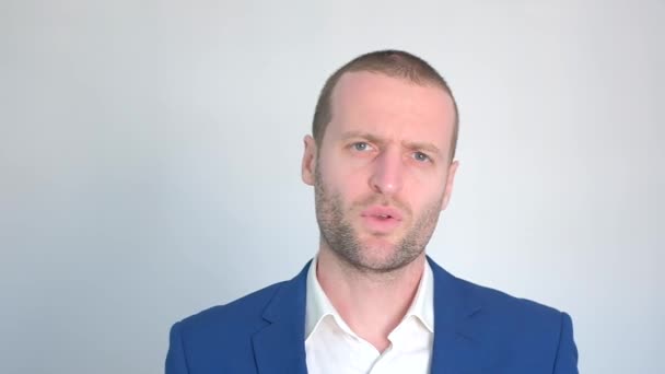 νεαρός επιχειρηματίας με μπλε σακάκι κοιτάζοντας την κάμερα σε λευκό φόντο - Πλάνα, βίντεο