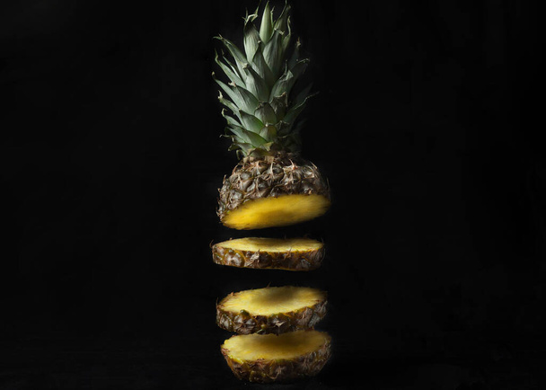 ripe pineapple cut into pieces on a black background.Levitation - Foto, Imagen