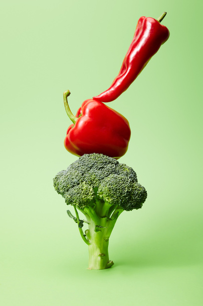 chili and bell peppers on broccoli on green   - Photo, Image
