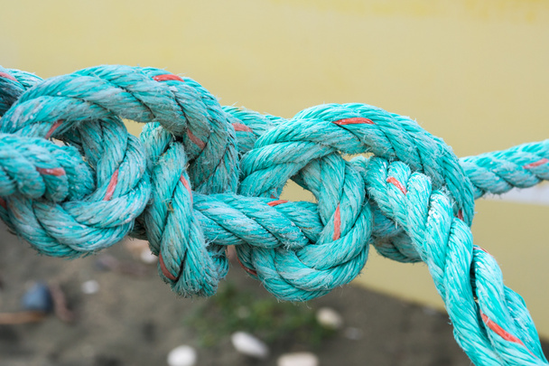 Old green rope knotted on a yellow background. Knot. Insoluble problem concept - Photo, Image