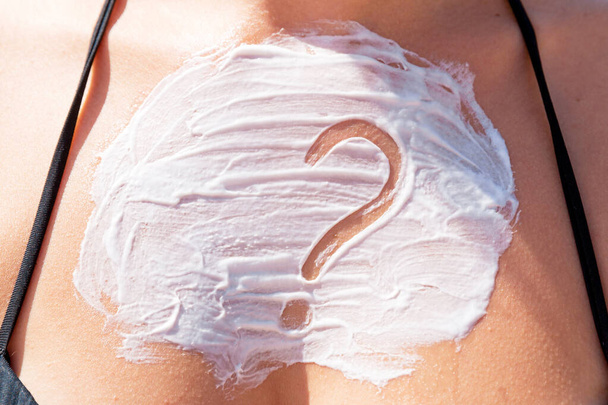 Знак вопроса: крем для загара на груди женщины на фоне моря
. - Фото, изображение