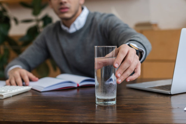 Cropped view of businessman taking glass of water in office - Photo, image