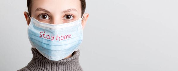 Portrait of a woman in medical mask with Stay home text and showing stop gesture at white background. Coronavirus self isolation concept. Respiratory protection. - Photo, Image