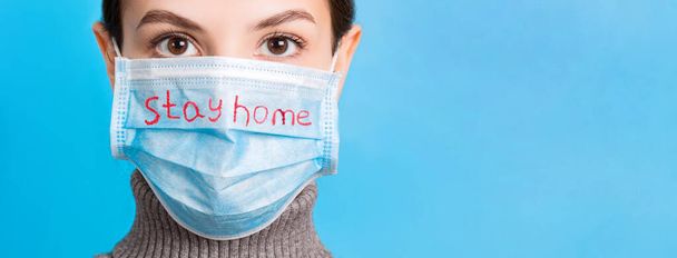 Ritratto di giovane donna che indossa una maschera medica su sfondo blu. Proteggi la tua salute. Concetto di coronavirus. - Foto, immagini