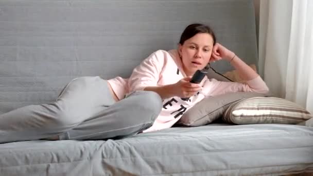 Young beautiful woman is lying on a sofa in the living room - Video