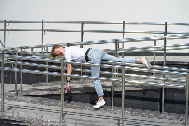 Short haired redhead smiling caucasian young woman lies on railing in urban center in hot summer day - Photo, Image