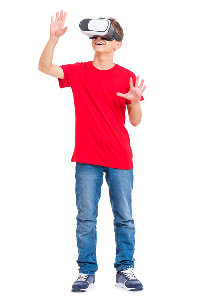 Full length portrait of young caucasian teen boy using virtual reality goggles. Funny teenager looking in VR glasses. Handsome child experiencing 3D gadget technology, isolated on white background. - Foto, imagen