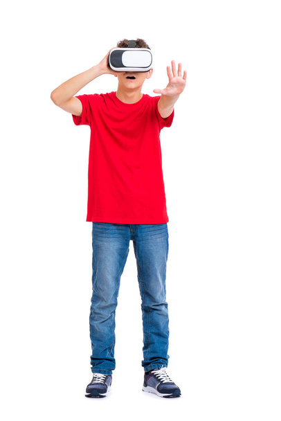 Full length portrait of young caucasian teen boy using virtual reality goggles. Funny teenager looking in VR glasses. Handsome child experiencing 3D gadget technology, isolated on white background. - Foto, Imagen