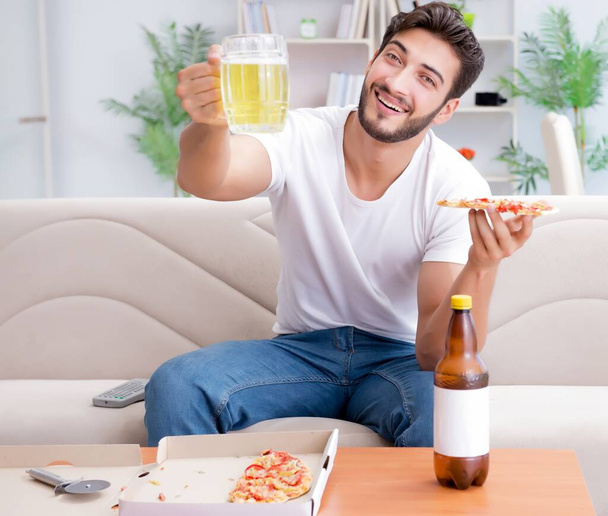 Homem comendo pizza tendo um takeaway em casa relaxante descansando - Foto, Imagem