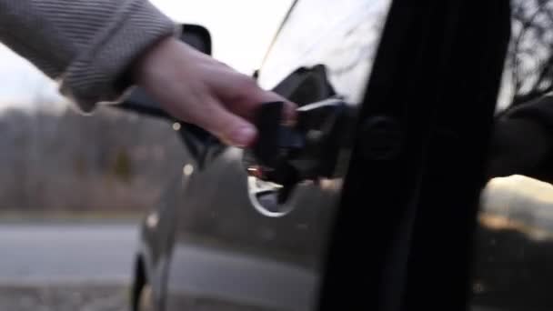 Close-up auto deurkruk, vrouw is het openen van zwarte auto deur en het krijgen van in de auto op straat - Video