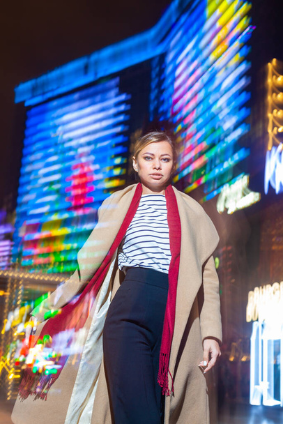 Cheerful girl in trendy apparel excited with night lights in Big City, beautiful brunette woman happy about spending evening free time in downtown with neon illumination. - Fotografie, Obrázek
