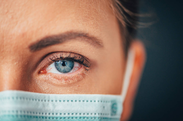 Γκρο πλαν φωτογραφία πορτραίτου, Μάτι του Γιονγκ Γυναίκα Γιατρός. Προστασία από μεταδοτική ασθένεια, coronavirus, υγιεινής προσώπου χειρουργική ιατρική μάσκα για την πρόληψη της λοίμωξης. Μαύρο φόντο - Φωτογραφία, εικόνα