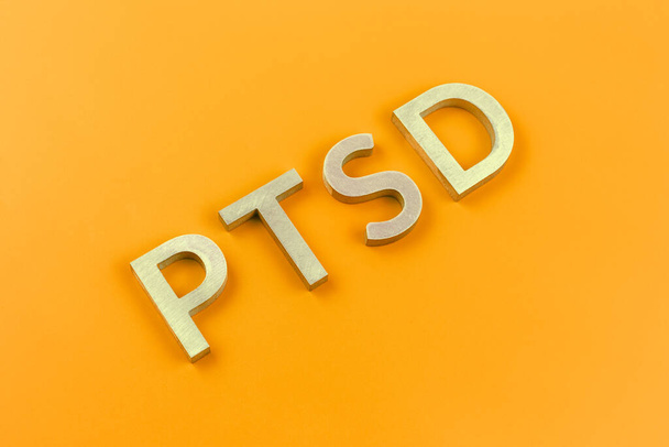 略称PTSD -心的外傷後ストレス障害-黄色のフラット表面上の銀金属文字で敷設 - 写真・画像