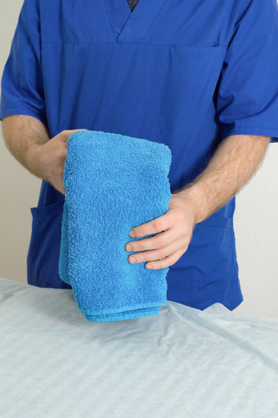 Close-up of a young male doctor hands. A man in a blue doctor uniform holds towel - Fotoğraf, Görsel
