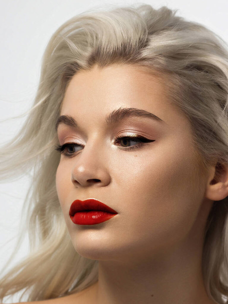 Close-up beauty of a female face with fashion evening make-up. Black liner on the eyes and extremely long eyelashes, on full lips matte scarlet lip color. Well-groomed skin after spa. red lipstick - Photo, image