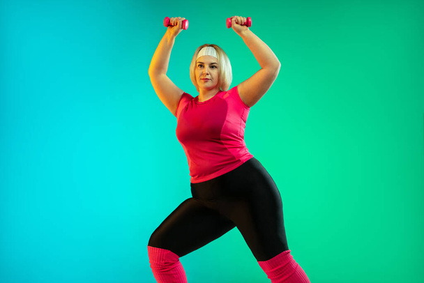 Young caucasian plus size female models training on gradient green background - Foto, Bild