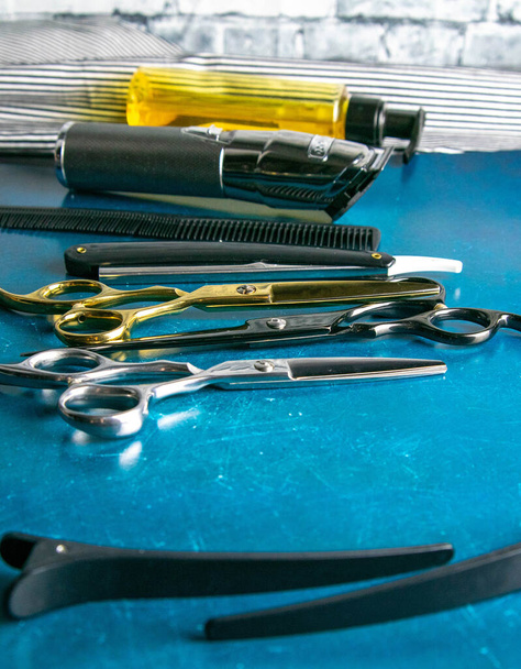 Friseurwerkzeuge, Schere, Haarschneidemaschine, Kamm, gefährliches Rasiermesser, Haargel stehen auf blauem Hintergrund. - Foto, Bild