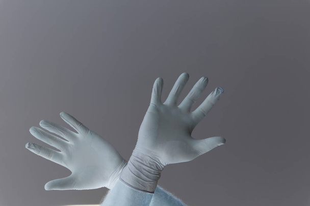 Handen van een man beschermd tegen het coronavirus. Witte latex handschoenen Bescherm uw handpalm tegen infecties, virussen en ziektekiemen. Bescherming van het huidisolatiesymbool tegen het gevaar van infectie. Obstructie, een barrière voor ziekten. - Foto, afbeelding