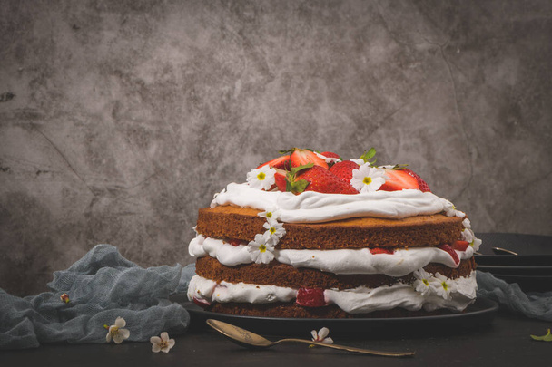 Strawberry cake, strawberry sponge cake with fresh strawberries and sour cream on a dark kitchen countertop. - Фото, изображение