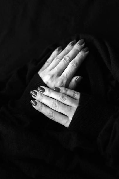 Close up on beautiful female hand with cute manicure on a Black background. black and white wool surface - Photo, Image