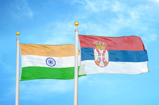 India y Serbia dos banderas sobre asta de bandera y fondo azul cielo nublado
 - Foto, Imagen