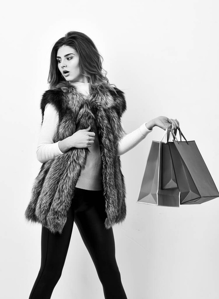 Girl makeup face wear fur vest white background. Lady hold shopping bags. Shopping concept. Fashionista buy clothes in shop. Sales and discount on black friday. Woman shopping luxury boutique - Photo, image