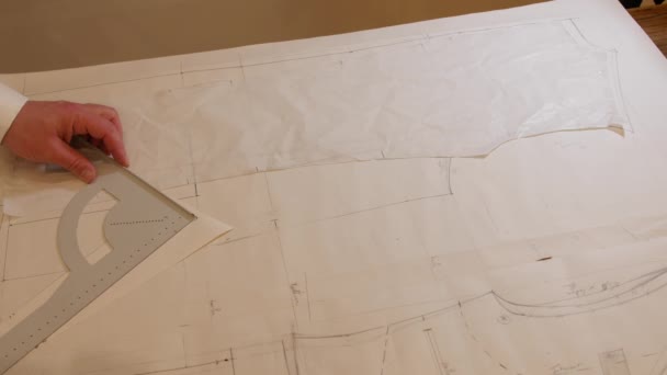 профессиональный Dressmaker портной рисунок костюм шаблон, измерения и рисунок рисунок контур на бумаге в ателье для будущего пиджака или костюма. Пошив модной одежды в студии в 4K
 - Кадры, видео
