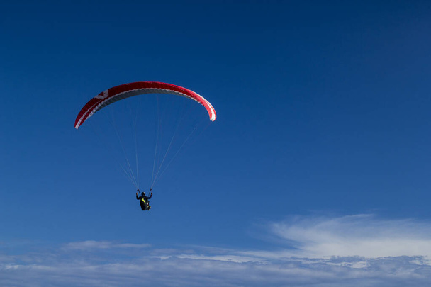 paragliding vliegen boven de wolken in de blauwe lucht - Foto, afbeelding