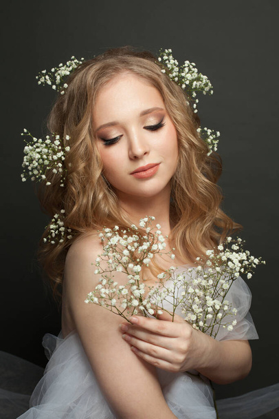 Cute young woman with long blonde curly hairdo and flowers - Foto, Imagen