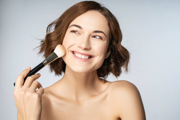 Positive delighted young female doing daily makeup - Fotoğraf, Görsel