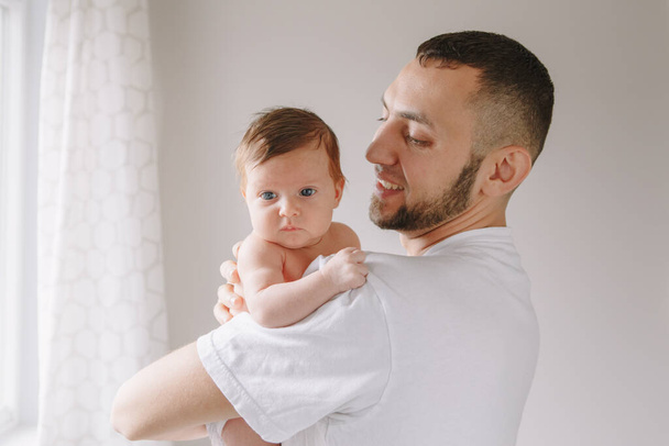 Happy Caucasian father holding newborn baby. Male bearded man parent rocking child daughter son on his hands. Authentic lifestyle candid moment. Young dad family life concept. - Photo, Image