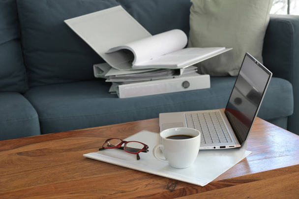 Домашній офіс на дивані з ноутбуком, зв'язувачем кілець і кавою, під час коронавірусної карантини люди повинні працювати у своїй вітальні, копіювати простір, вибраний фокус
 - Фото, зображення