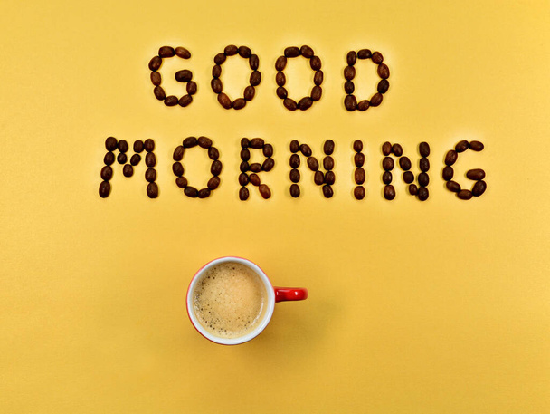 Een kop koffie, met de inscriptie Goedemorgen. Kopje koffie, op een geïsoleerde achtergrond. Inscriptie Goedemorgen, gemaakt van koffiebonen. - Foto, afbeelding
