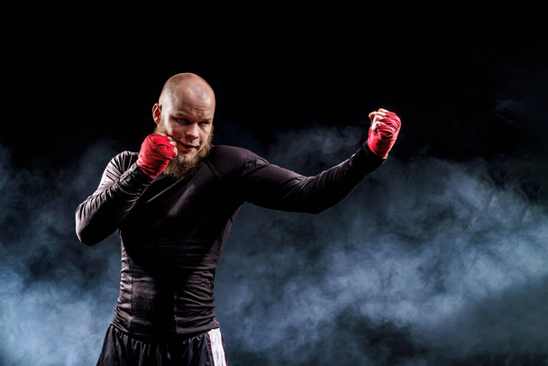Sportsman boxer fighting on black background with smoke. Boxing sport concept - Фото, зображення