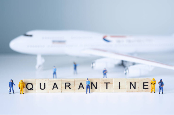 Group of toy people isolate a plane and its passengers. Quarantine concept. - 写真・画像