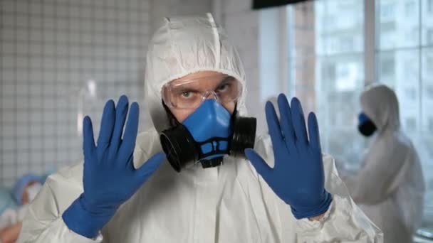 Doctor wearing respirator and protective suit making a stop gesture to camera. Dont worry. Hospital. - Materiaali, video
