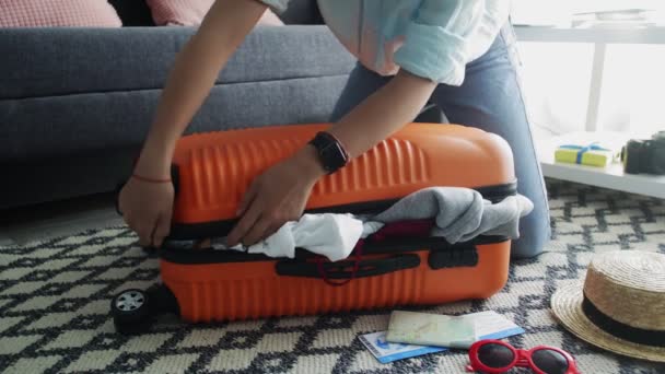 Nettes Mädchen steht auf ihren Knien auf einem überfüllten orangefarbenen Koffer und versucht, ihn zu schließen - Filmmaterial, Video