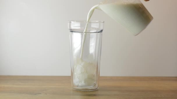 Milk pouring into glass with ice.Making Iced Coffee. - Video