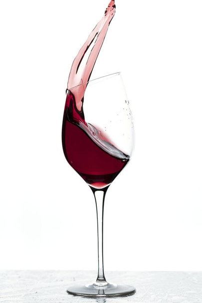 Közelkép a fröccsenő vörösbor üveg elszigetelt fehér alapon.  - Fotó, kép