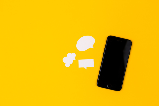 Смартфоны с бумажными пузырями речи на желтом фоне. Концепция коммуникации. Вид сверху. Принято. Состав бумаги
 - Фото, изображение
